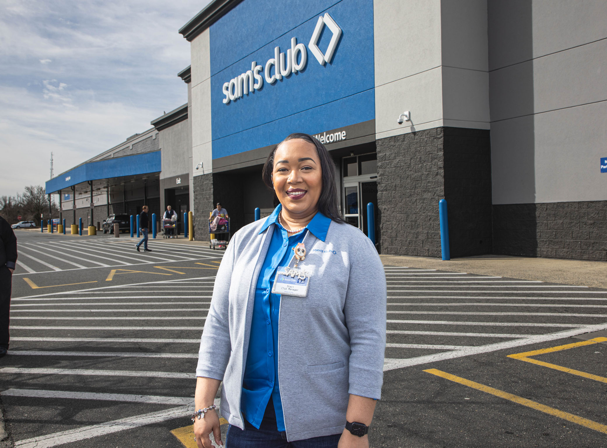 female associate smiling at the camera in front of a Sam's Club store front