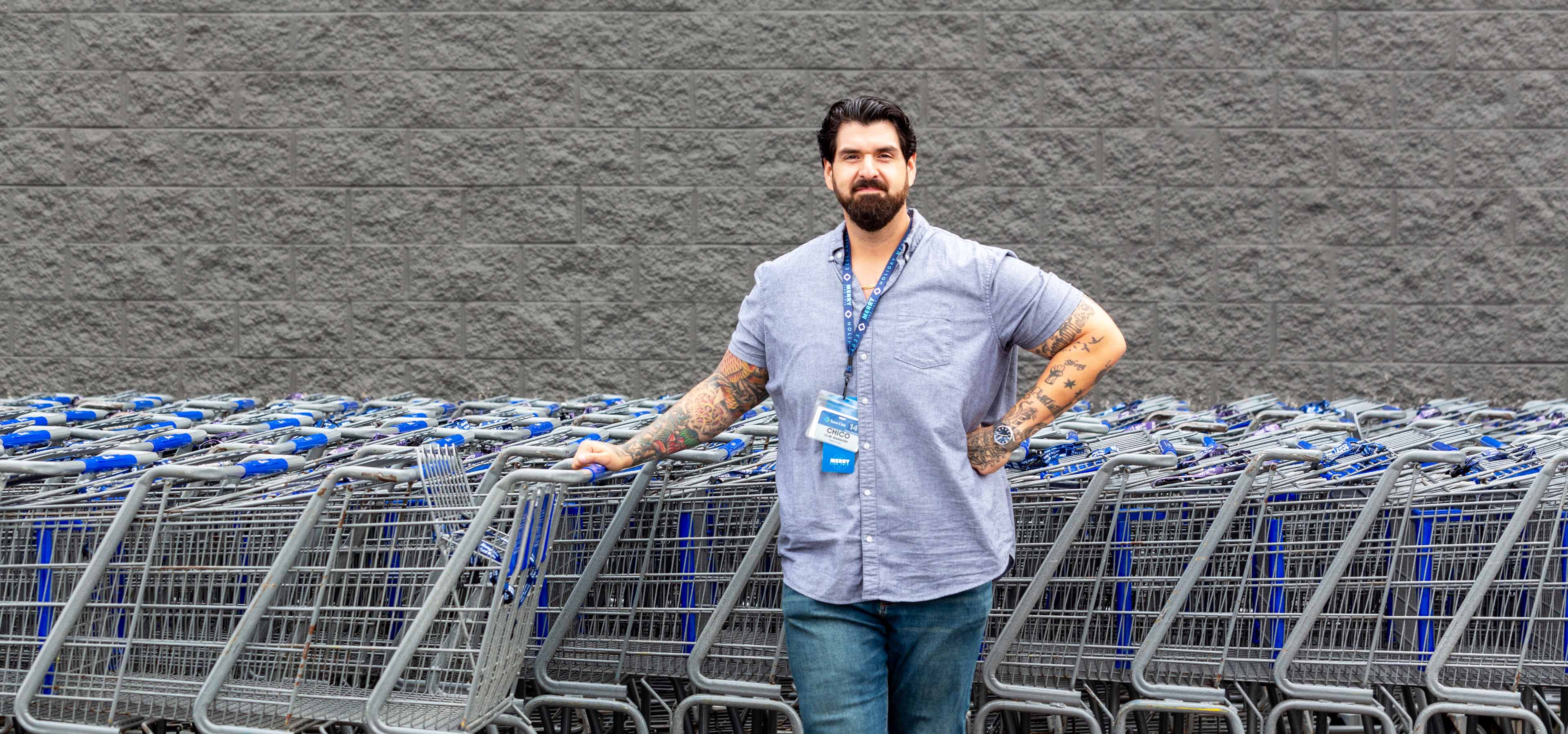Chico Montenegro posing for the camera in front of a row of Sam's Club shopping carts