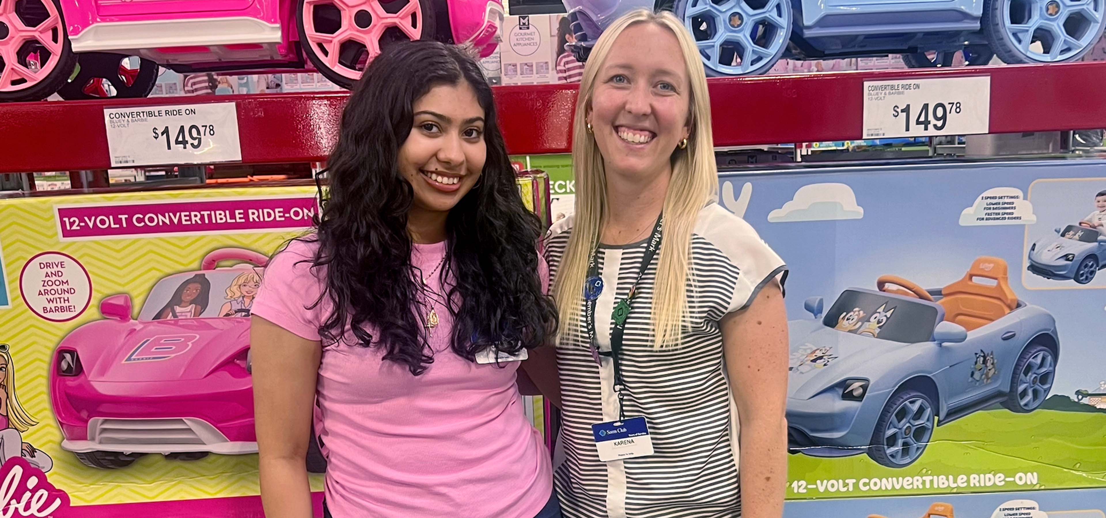 Diana and Krystle smile in front of the toy aisle of Sam's Club