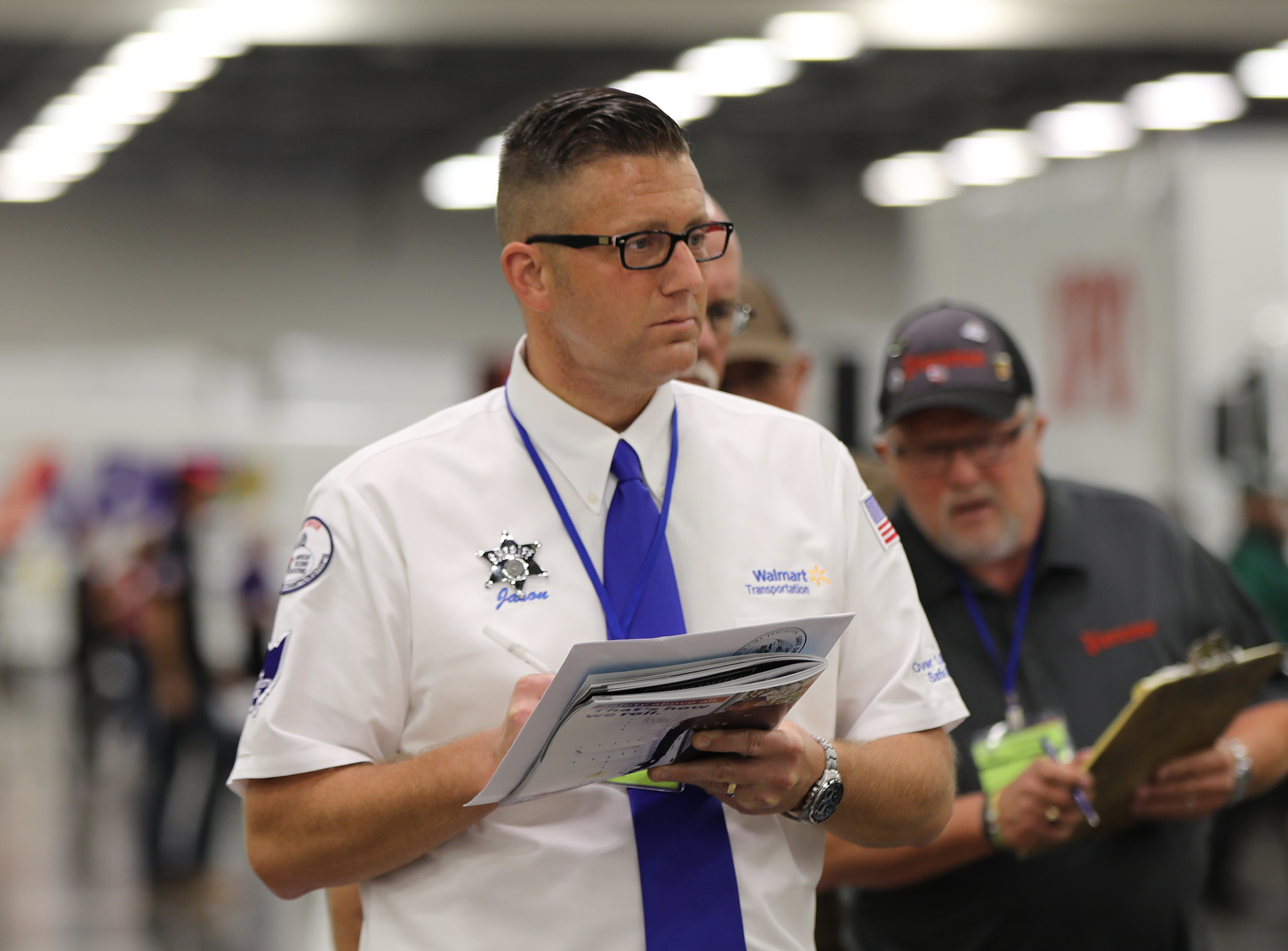 A walmart driver at the national truck competition holding a notebook taking notes
