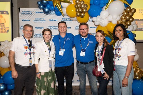 A group of six colleagues pose together at a Walmart Integrity in Action Award event. 