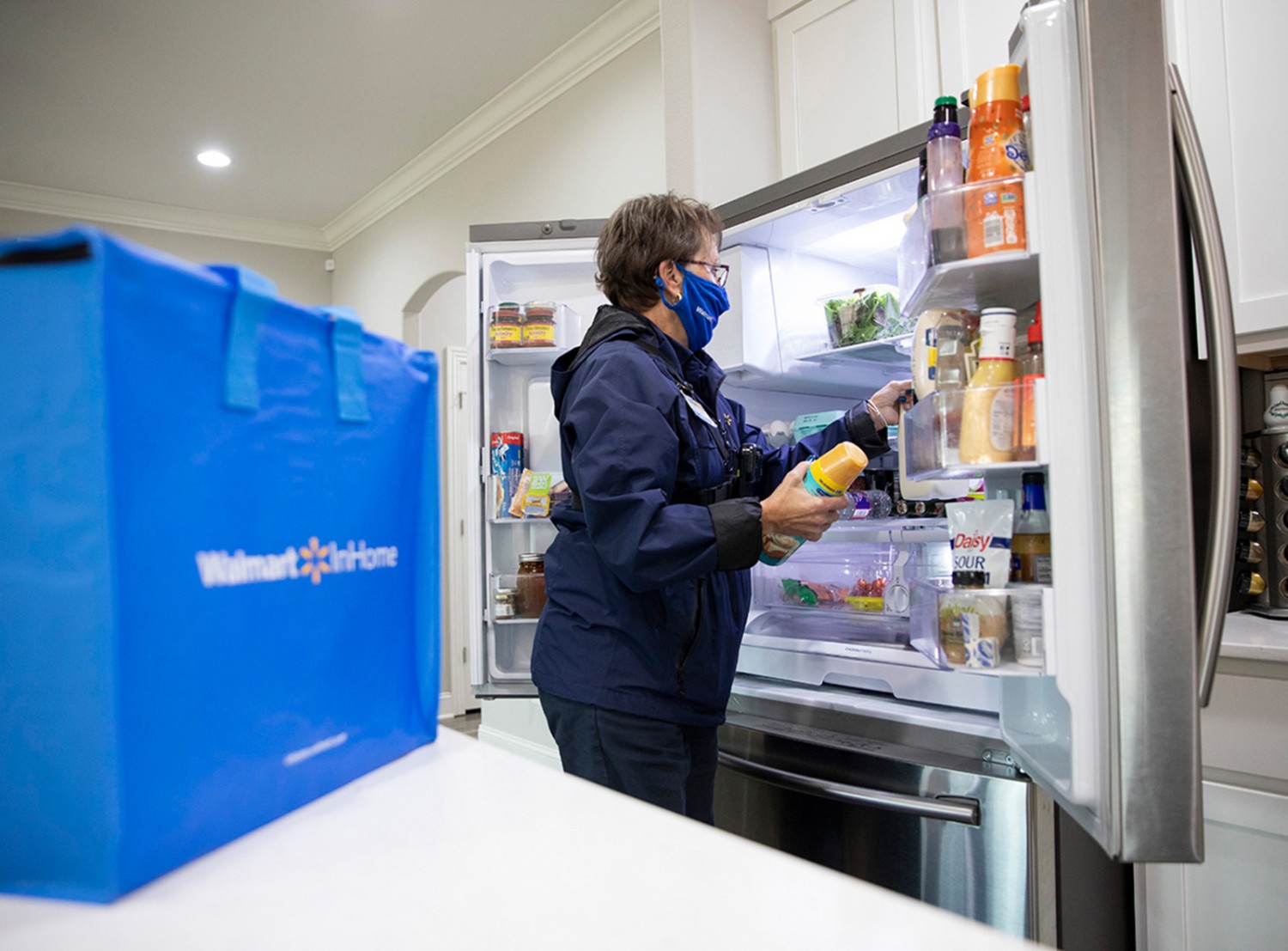 Kathleen puts groceries in a customer's refrigerator.