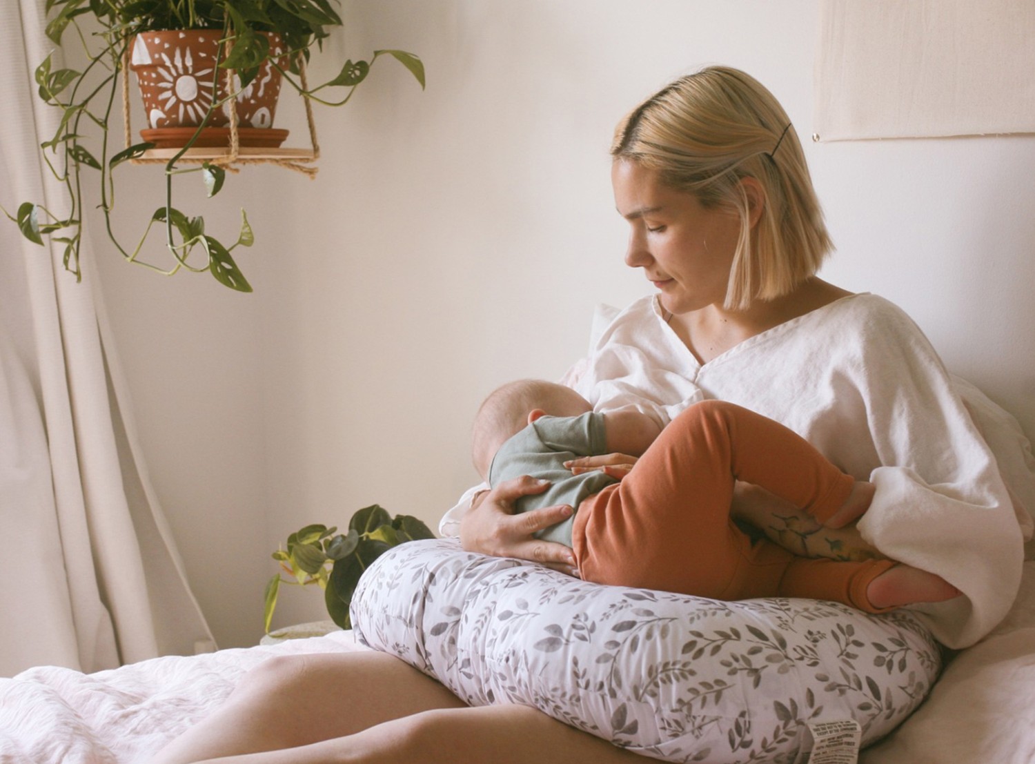 New mom breastfeeds her baby on her lap.