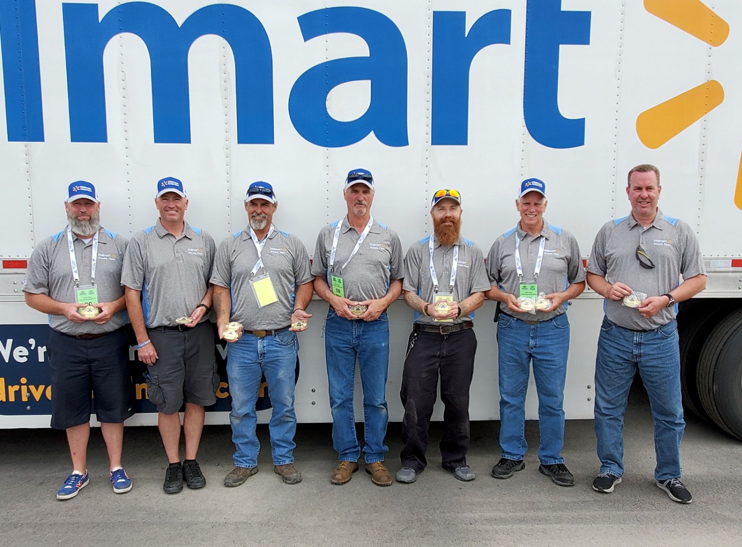 Walmart champion drivers pose in front of a Walmart semi trailer.
