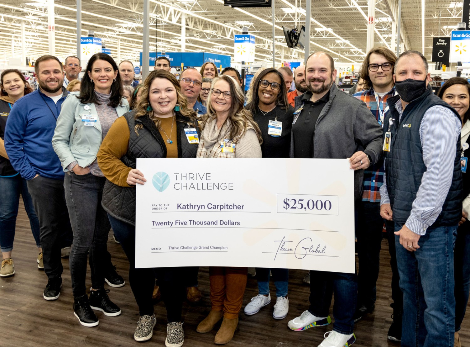 Photo of smiling associates in a store holding a large check made out to Kathryn Carpitcher for $25,000
