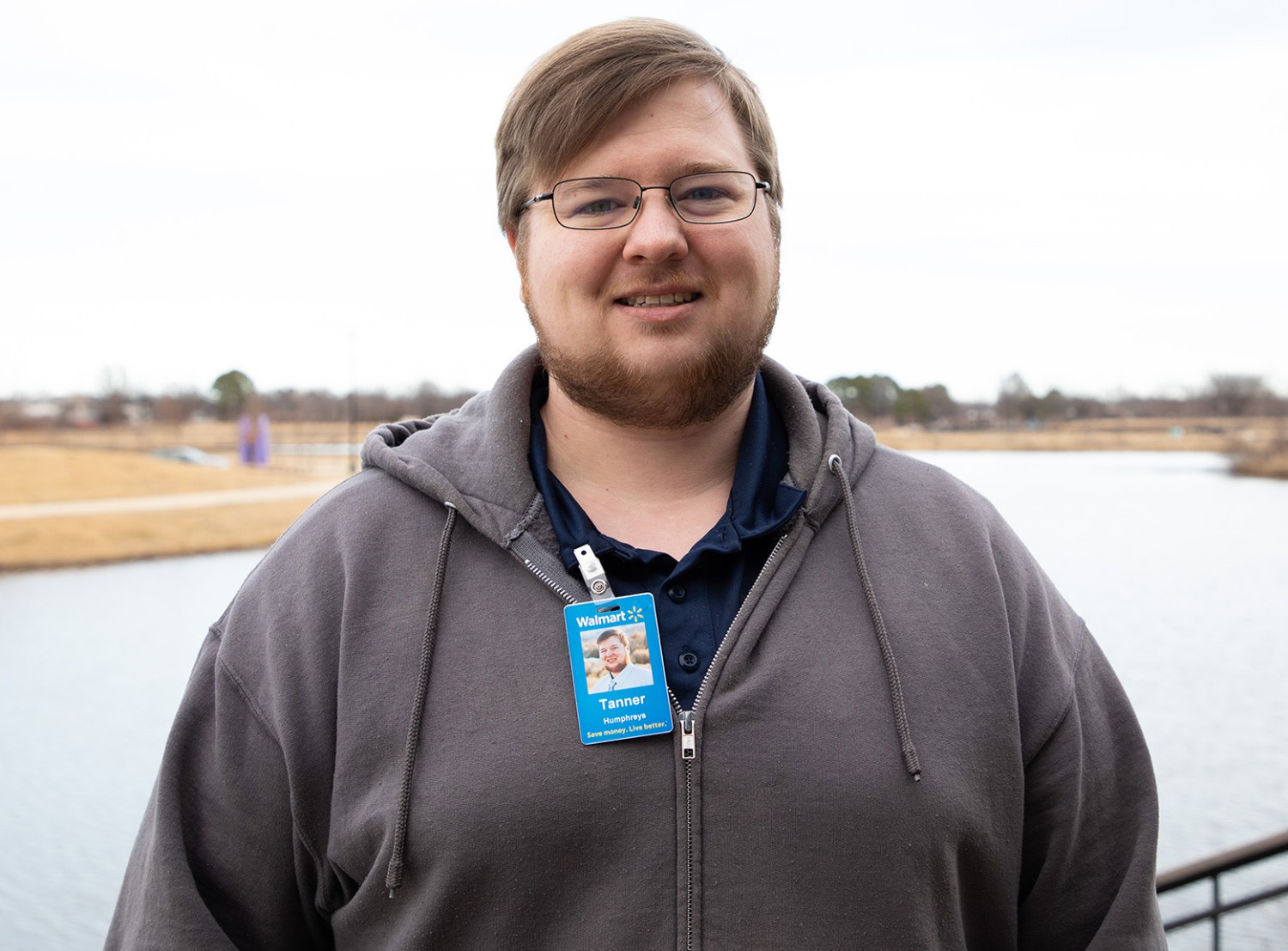 man smiling at the camera in front of a lake