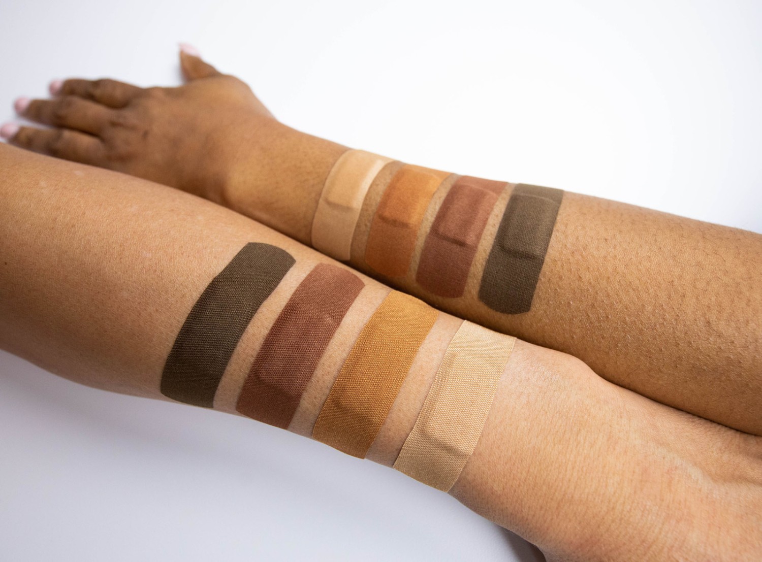 photo of a variety of skin tone bandages on two individuals arms