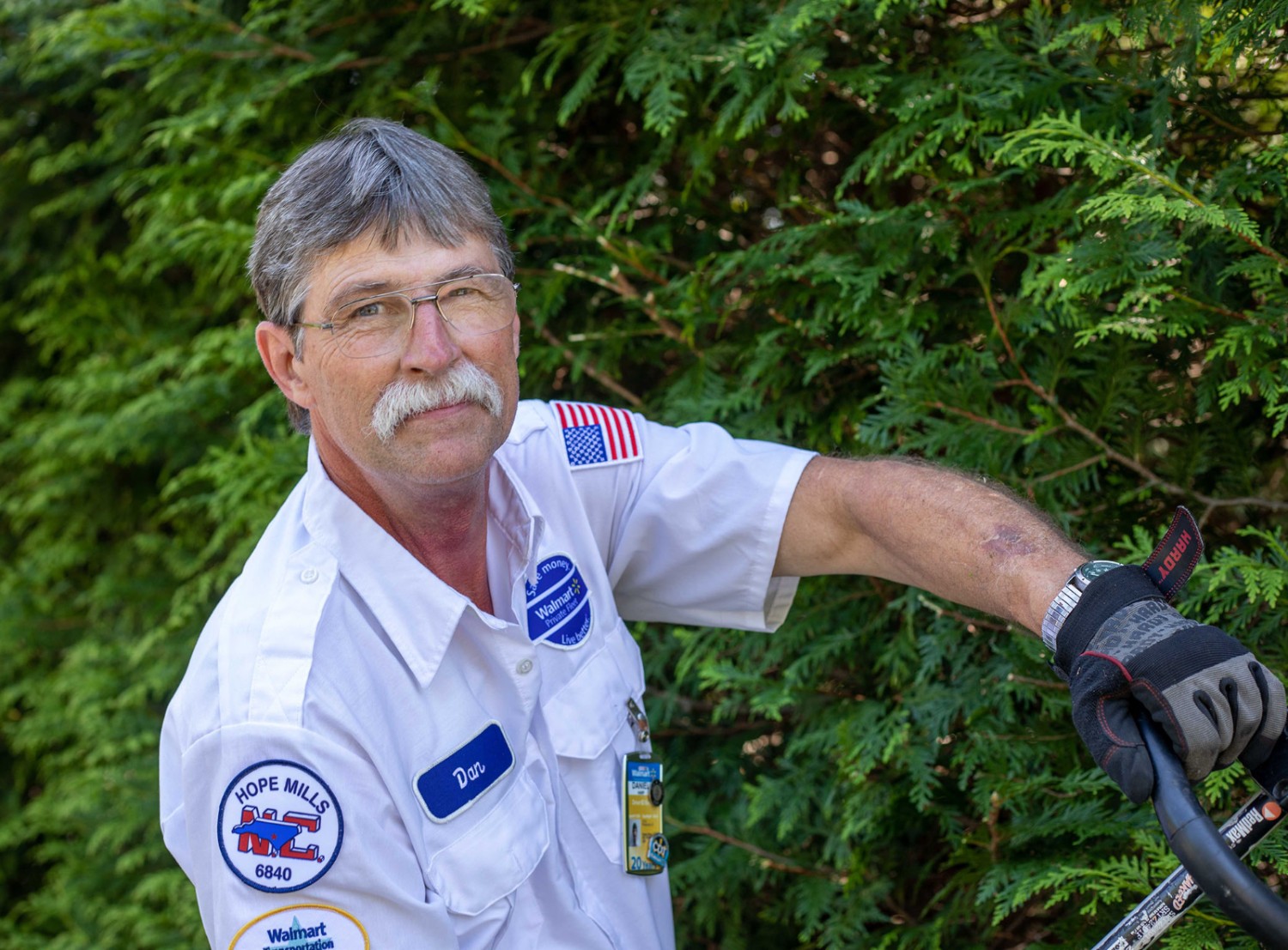 Man trimming down bushes smiling at the camera