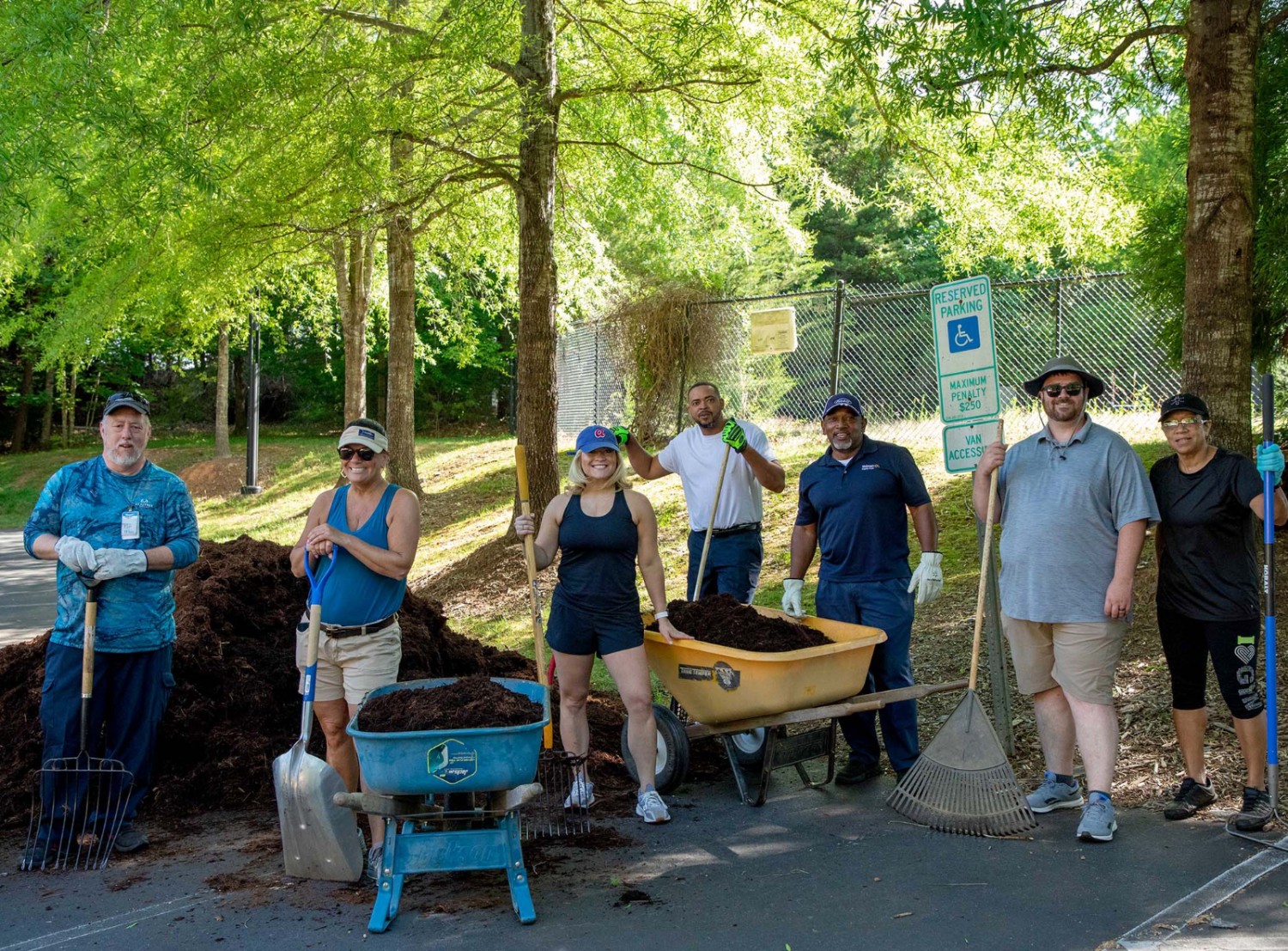 Associates standing behind wheelbarrows of soil