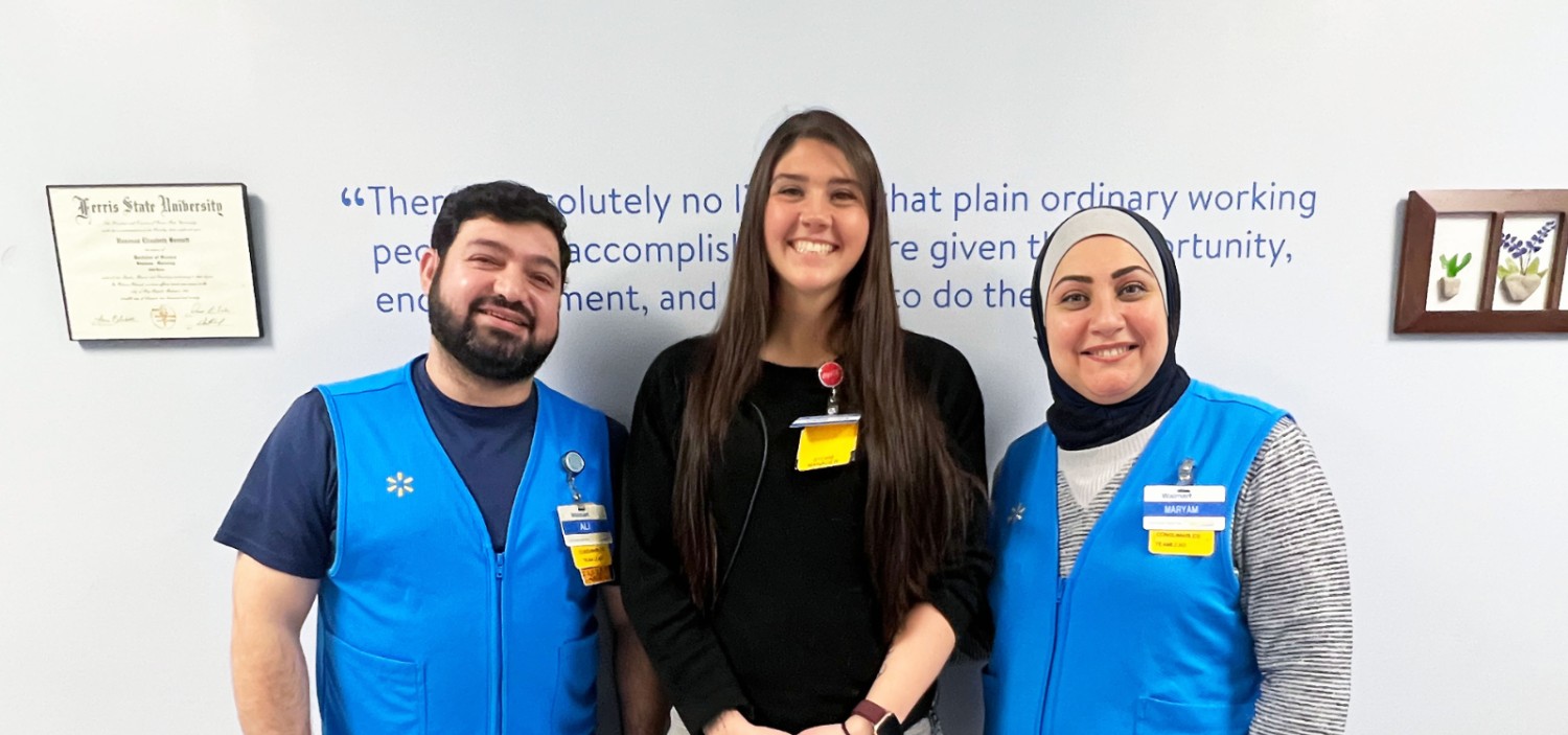 two walmart associates with their manager smiling at the camera