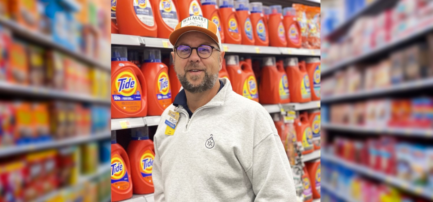 male associate in a Walmart aisle smiling at the camera