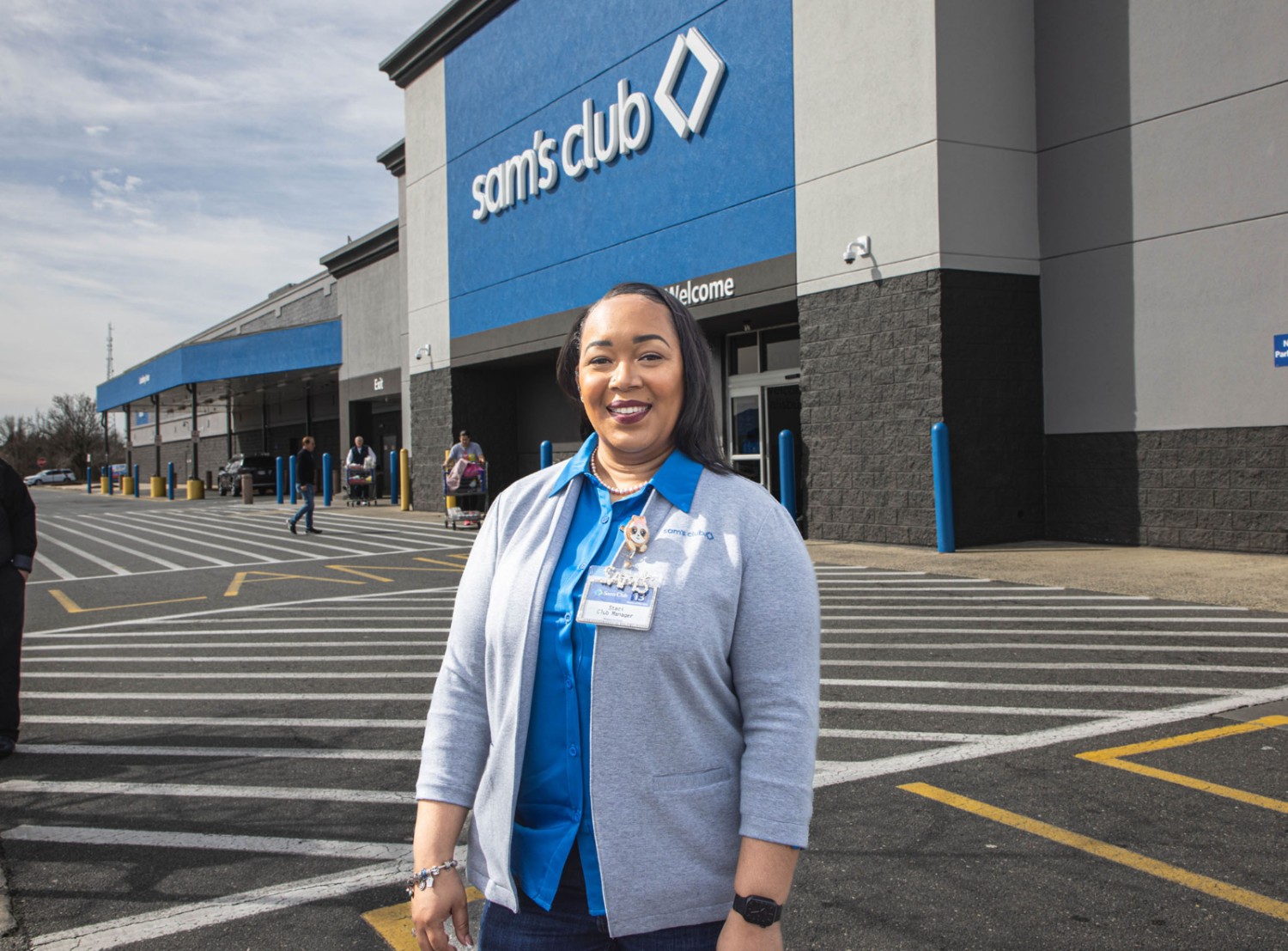 female associate smiling at the camera in front of a Sam's Club store front