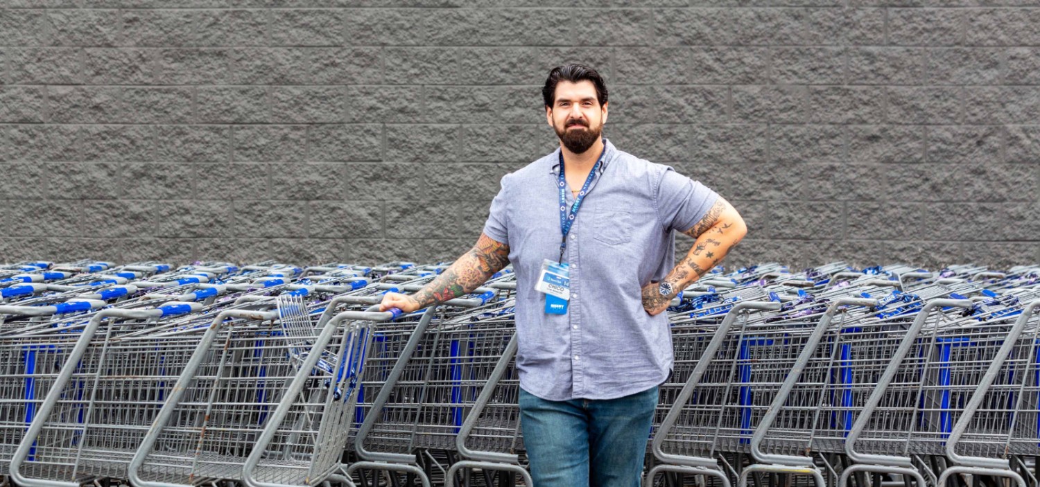 Chico Montenegro posing for the camera in front of a row of Sam's Club shopping carts