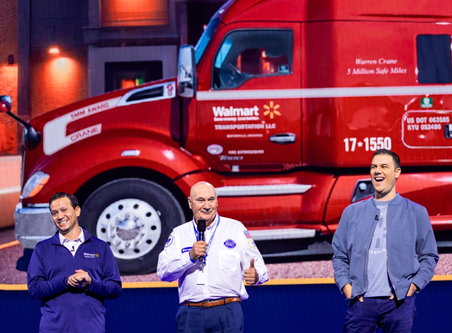 Dave Guggina, Fernando Cortes, and associate Warren Crane on stage in front of an image of a red truck.