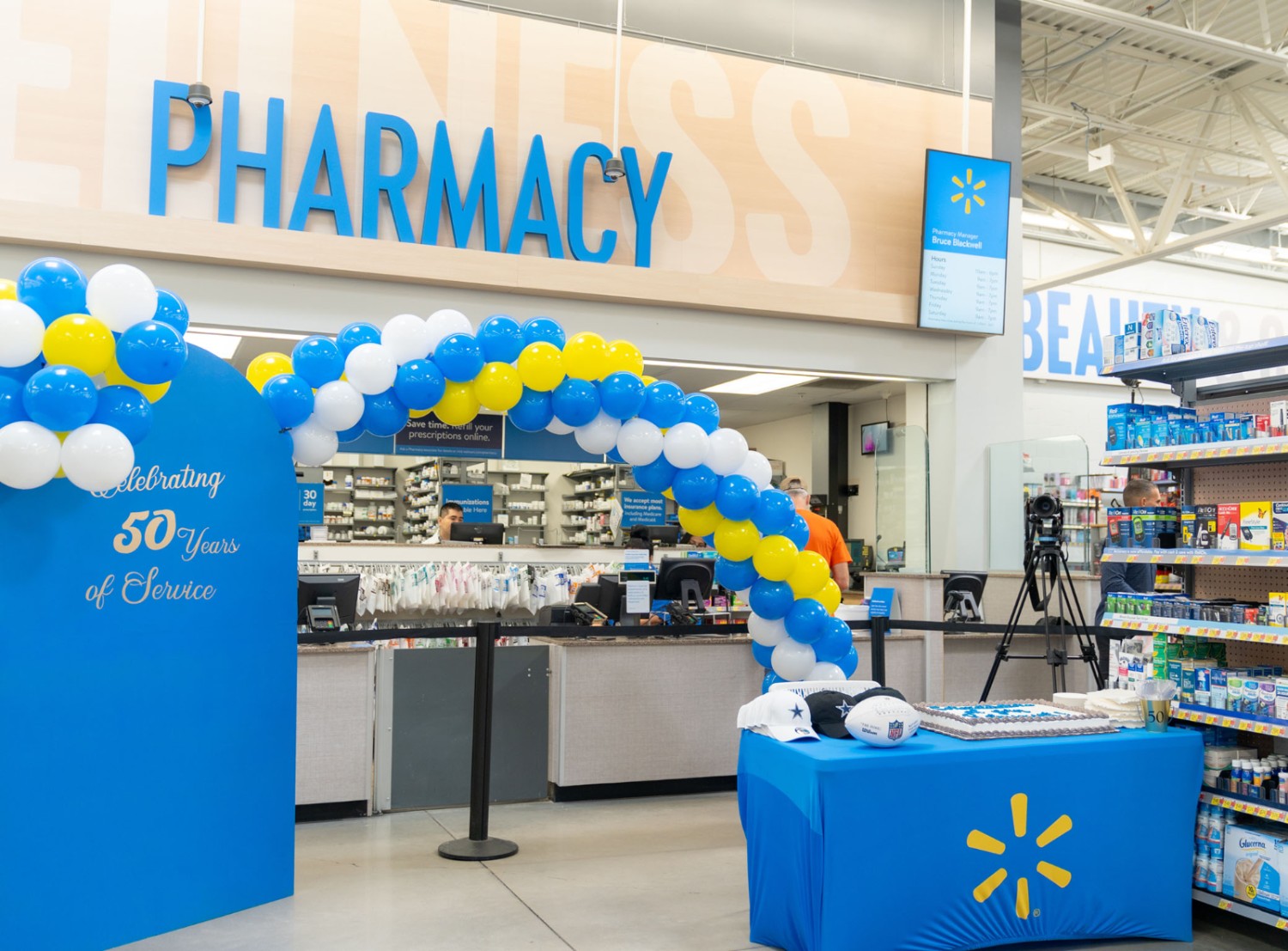 Picture of the front of a Walmart Pharmacy with a ballon arch and a board that reads "Celebrating 50 years of service"