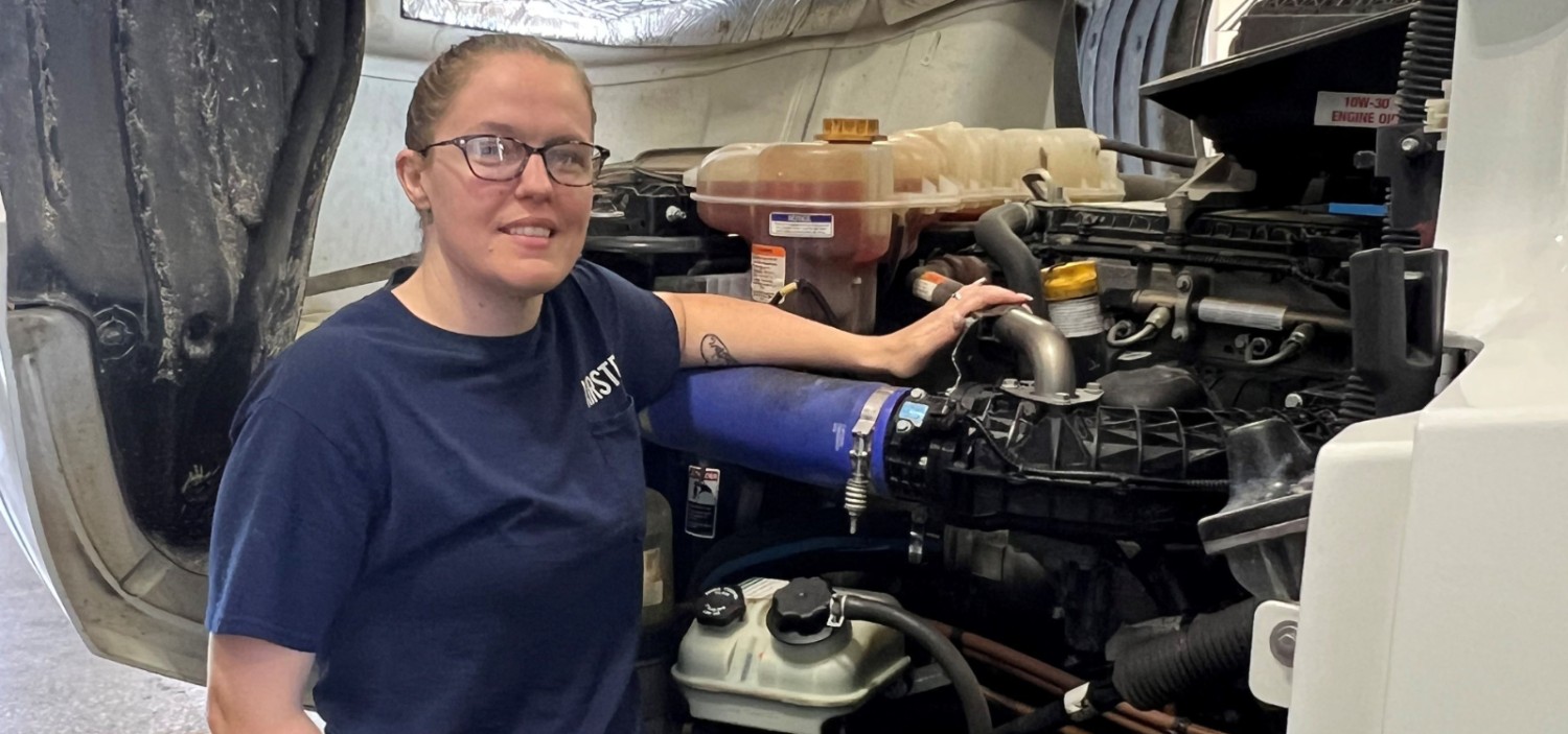 Kristee posing in front of an engine of a truck