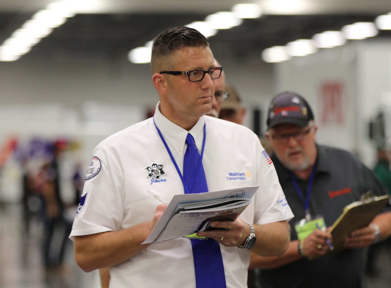 A walmart driver at the national truck competition holding a notebook taking notes