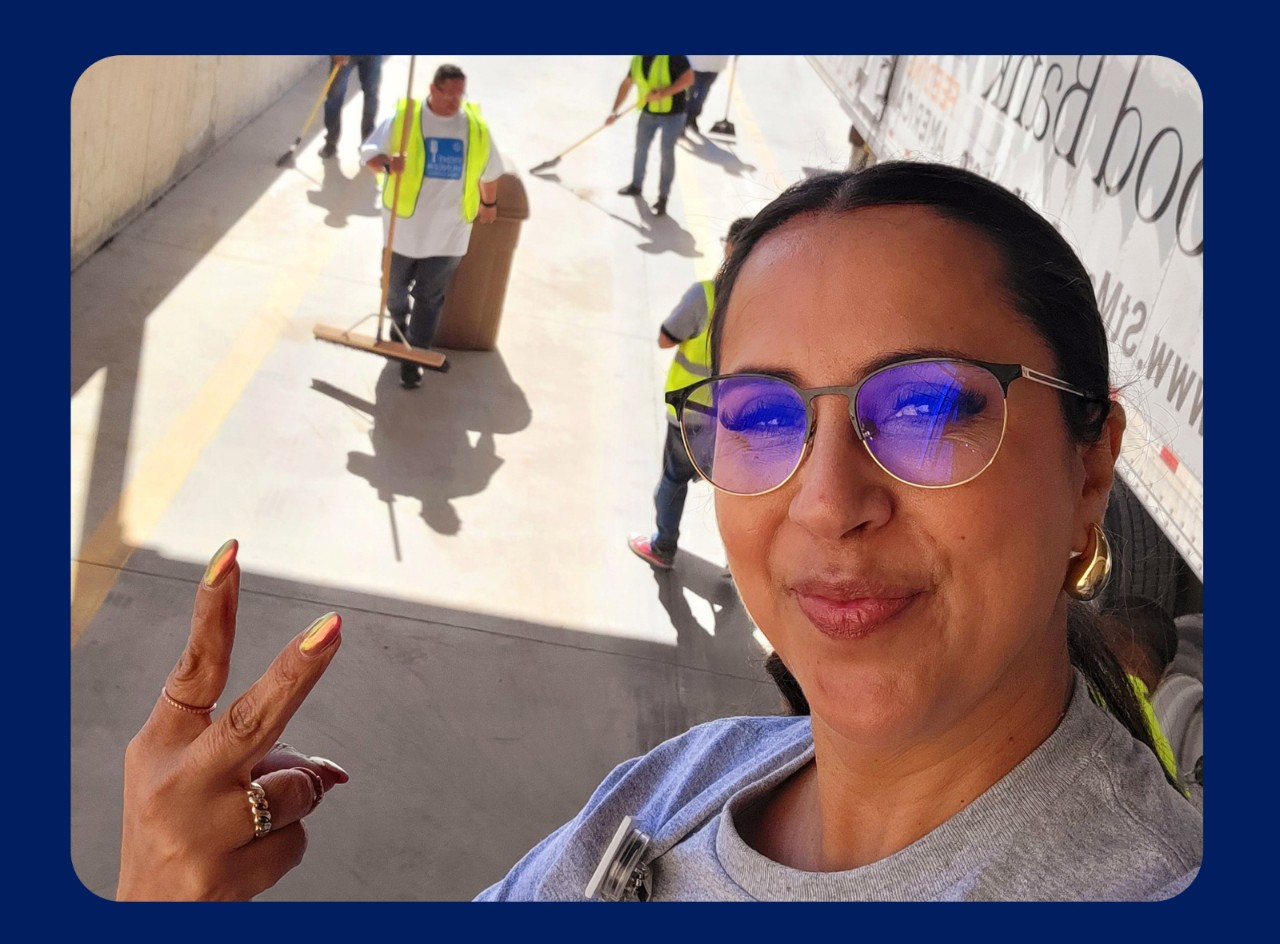 Walmart store manager Oti smiles in the foreground as volunteers help the Yuma Food Bank in the background.