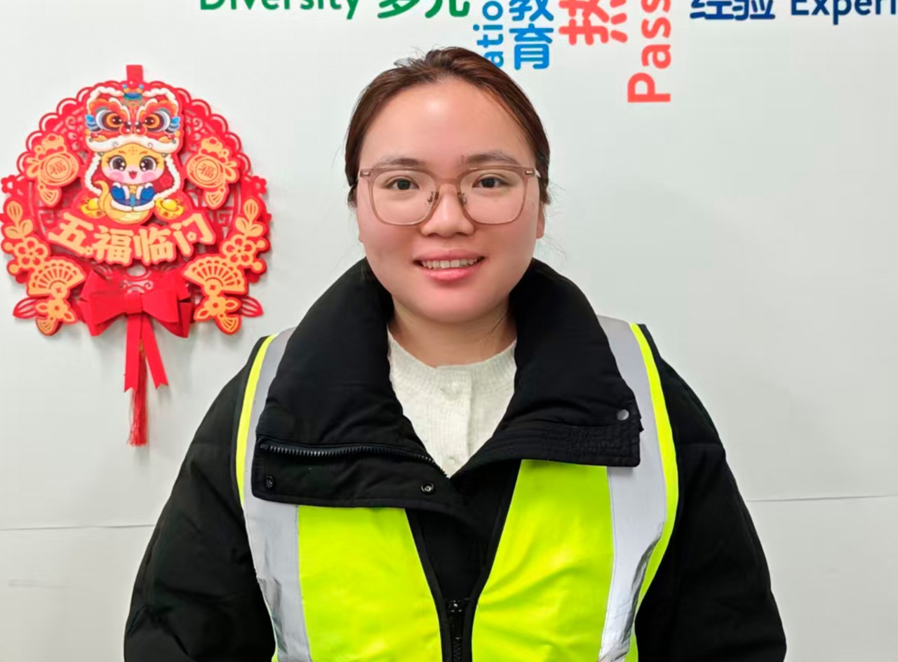 Walmart associate Zi XIn smiles in front of wall with Chinese decoration.