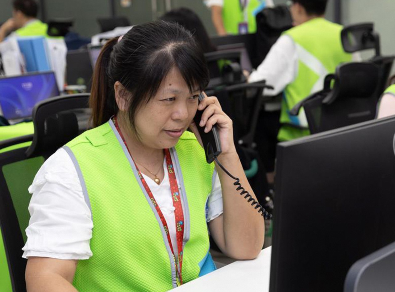 Walmart associate Yang Xiaomei talks on a phone at desk in front of a computer.