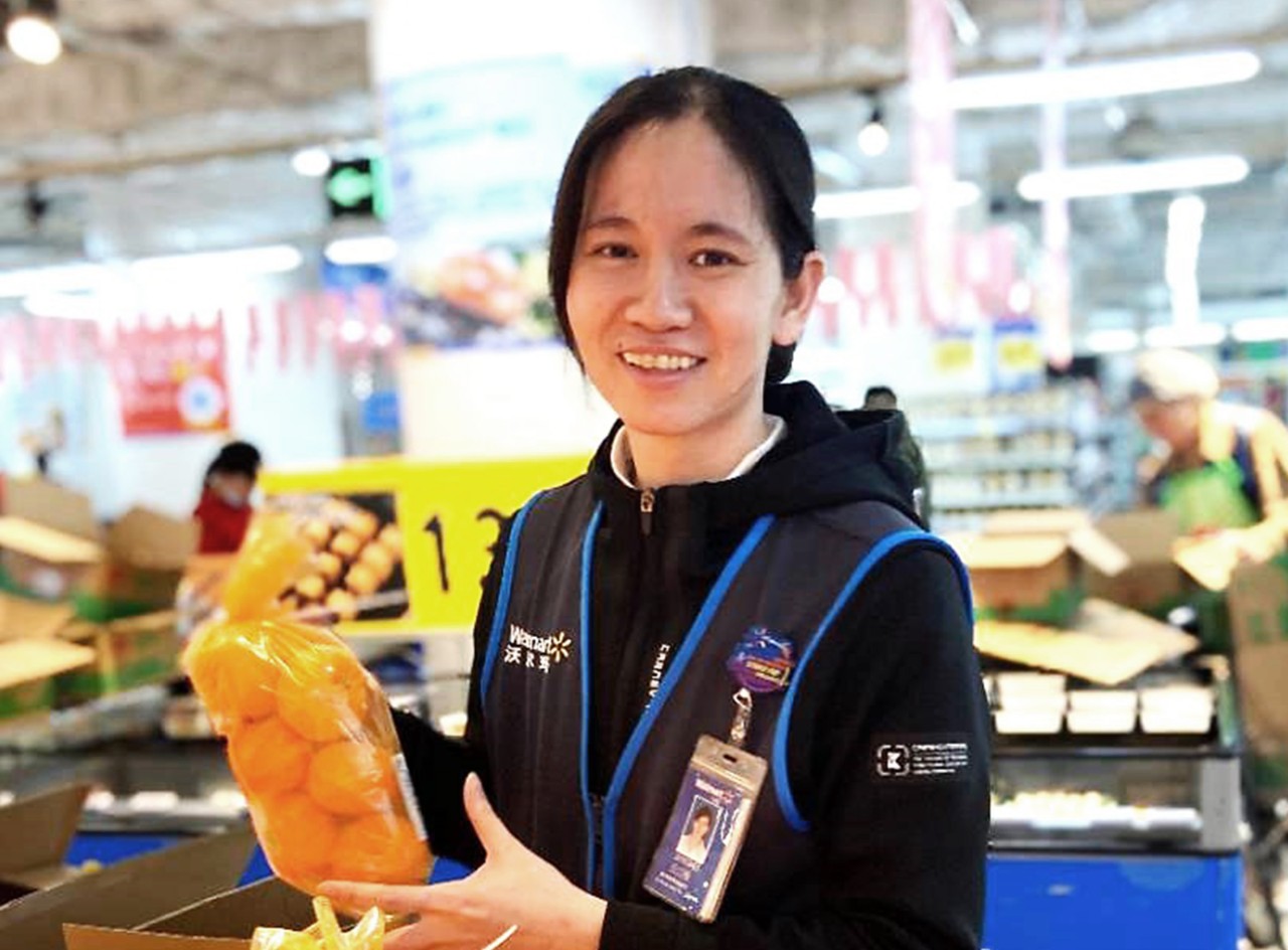 Walmart associate Qiu Jiangmei smiles in her store’s produce department.