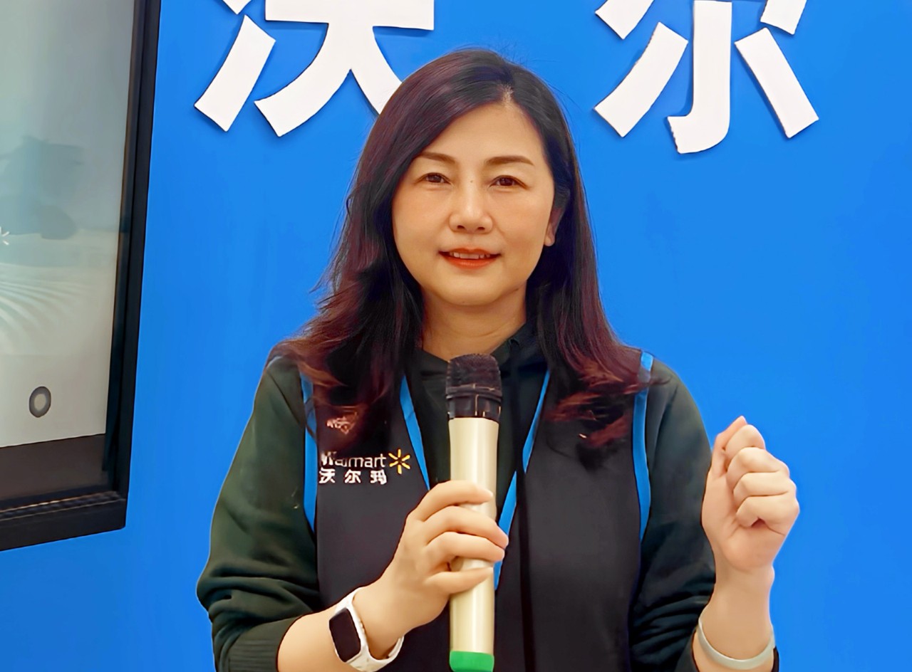 Walmart associate Yang Hua holds a microphone and smiles.
