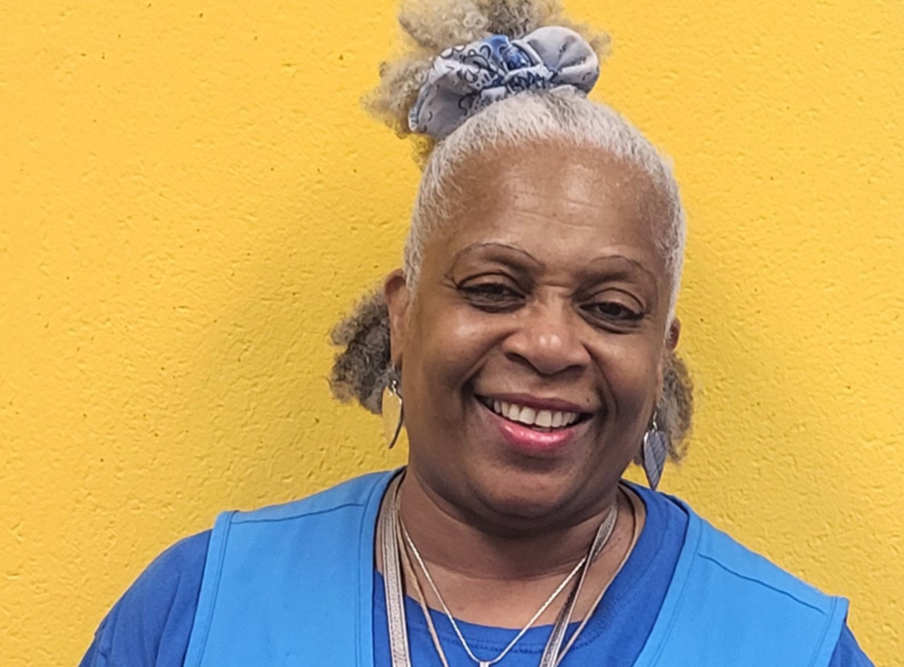 Walmart Cashier Renee Wynn smiles against a bright yellow background.
