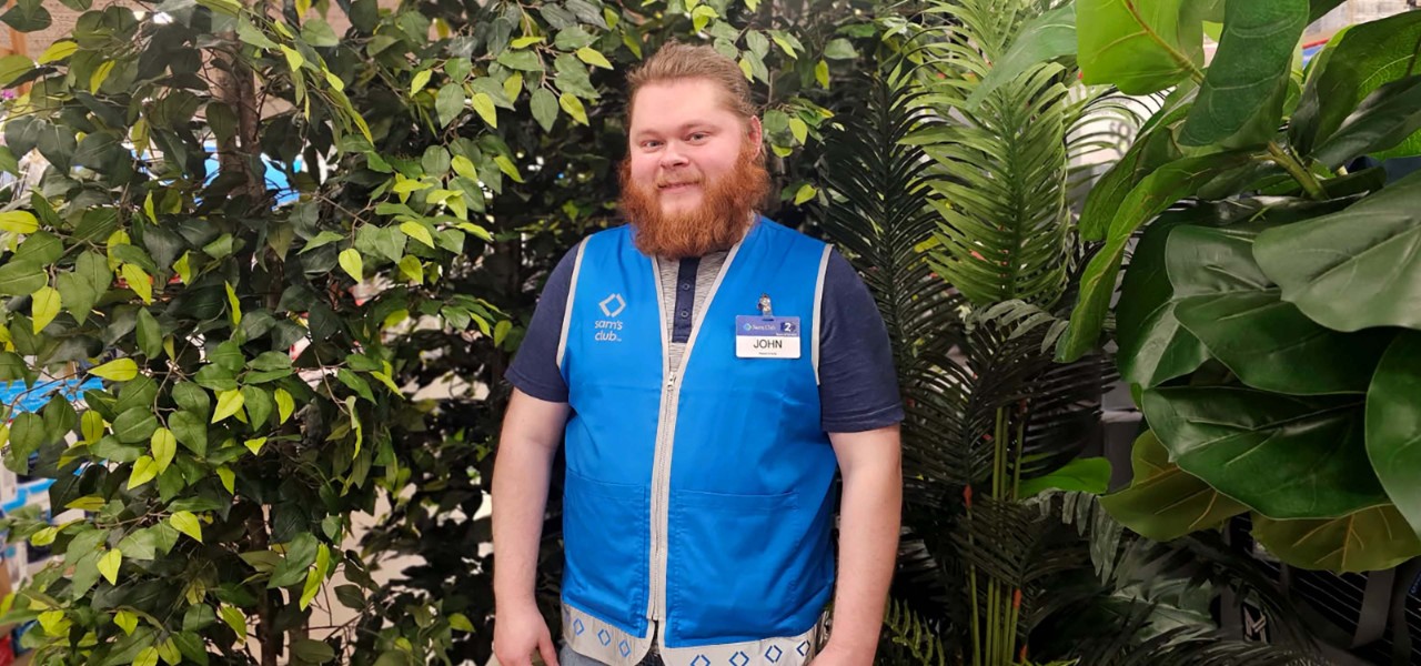 Sam’s Club associate John Roach stands among green plants.